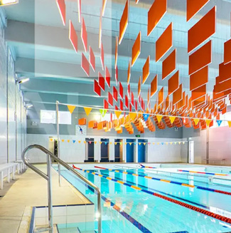 Large orange and yellow acoustic baffles over an indoor swimming pool.